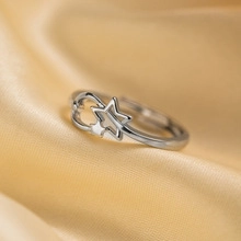 Detail macro shot of a silver star and moon adjustable ring on champagne silk background