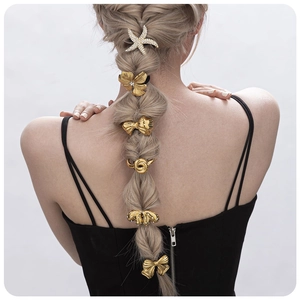 Gold starfish hair clip with crystals and butterfly pins on a braided hairstyle