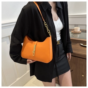 Detail of orange faux leather shoulder bag with gold chain strap and metallic clasp