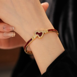 Detail eines vergoldeten Armbands mit roter Emaille-Kalebasse und Zirkonia-Steinen