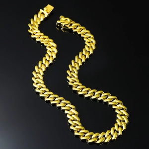 Polished golden stainless steel Cuban link chain for men in a dynamic S-curve on black base