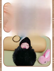 Detail of plush baby doll keychain with knit hat and soft faux fur ball texture