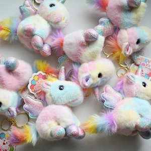 Close-up of fluffy rainbow unicorn plush keychains with sparkly wings and golden clips
