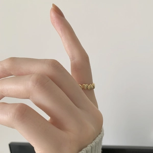 Close-up of golden heart-shaped band ring worn on finger with mirror-polished finish