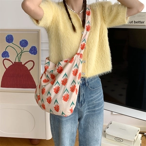 Close-up of woman wearing a floral canvas shoulder bag with orange flower patterns