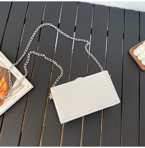 Detail van zilveren metallic box clutch met ketting op donkere houten ondergrond