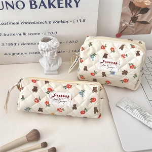 Vue détaillée de la trousse de maquillage et du plumier matelassés avec motifs ours et fleurs.