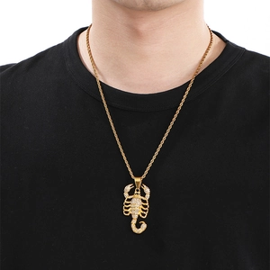 Détail du pendentif roi scorpion doré avec strass brillants sur une chaîne torsadée
