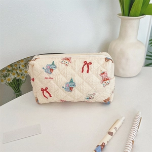 Dettaglio del beauty case trapuntato beige con motivi di animali carini e cerniera lampo