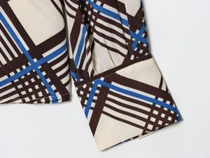 Détail des poignets de chemise à carreaux avec imprimé géométrique et finitions soignées