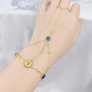 Detailed shot of a gold hand chain bracelet with blue evil eye beads and a coin charm