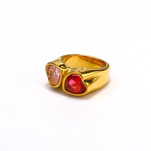 Detail showing two heart-shaped pink and red gemstones on a wide 18k gold band
