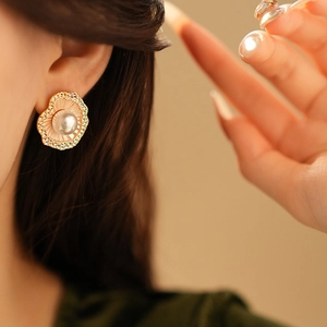 Vue macro d'une boucle d'oreille perle irrégulière avec bordure dorée et strass brillants