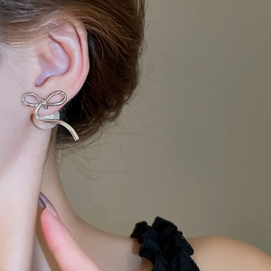 Close-up of 14K gold plated silver bow earrings with elegant white pearls on model