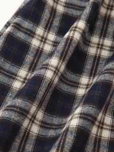 Detailed macro view of the blue and brown plaid fabric texture with woven cotton fibers