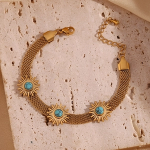 Macro detail of gold-plated mesh bracelet with turquoise-colored sunburst charms