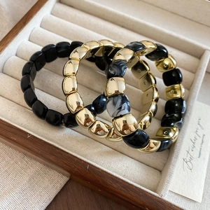 Three-piece gold and marble bead bracelet set displayed in a wooden jewelry gift box