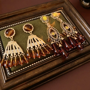 Close-up of vintage gold tassel earrings with tiger eye stones and diamonds on green velvet