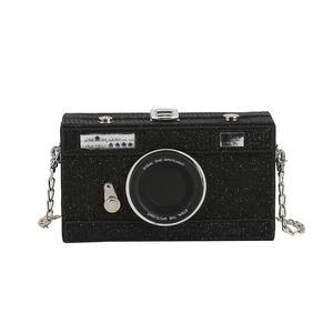 Glittery black camera-shaped clutch bag with silver chain strap and spotlight text