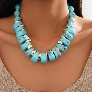 Close-up of chunky turquoise resin beads and gold spacer rings on a fashion necklace
