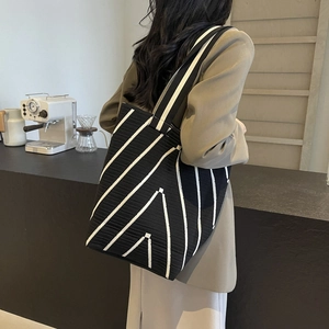 Minimalist black and white striped knitted tote bag for women shown in a cafe setting