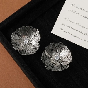Close-up of silver hollow wire floral earrings with sparkling cubic zirconia on black velvet