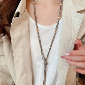 Close-up of a stylish layered tassel necklace with metallic beads on a model