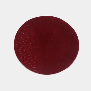 Détail d'un béret tricoté bordeaux avec des strass rouges étincelants en motif de vagues