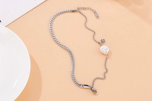 Detail of silver S925 snake chain necklace with baroque pearl and clover pendant