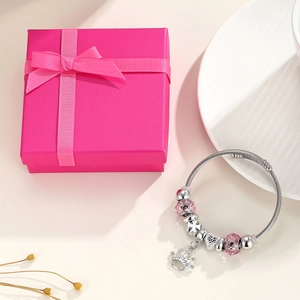 Pink crystal crown charm bracelet with heart beads on a white plate in a pink gift box