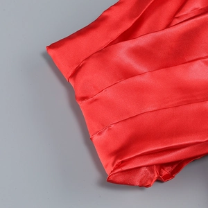 Close-up of elegant red satin fabric with pleated details and glossy silk texture