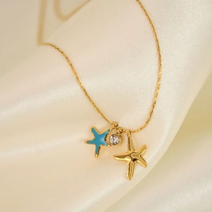 Gold starfish necklace with blue enamel pendant and rhinestones on white silk background