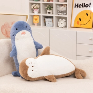 Cute plush shark and seal pillows in blue and brown on a cozy white sofa