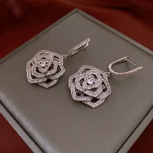 Silver hollow flower drop earrings with white zircon stones on a jewelry display box