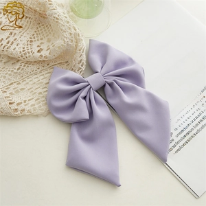 Detailed close-up of light purple double-layered fabric bow hair clip on a lace surface