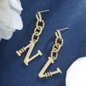 Macro view of gold chain earrings with N and V letter pendants and zircon details
