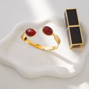 Gold plated stainless steel open bangle featuring two large oval red agate gemstones