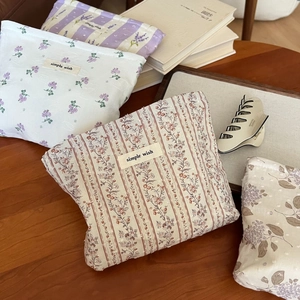 Detailansicht kleiner Baumwolltaschen mit Blumenmuster und Etikett auf Holzoberfläche