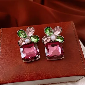 Floral pearl earrings with colorful crystals and magenta pendants on a luxury leather box