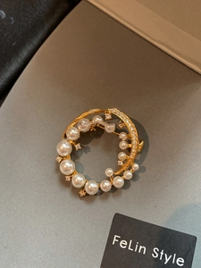 Macro detail of 24k gold-plated round brooch with elegant pearls and sparkling zircons