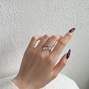 Detail of silver S925 ring with pink heart diamond and clear pear shape stone on hand