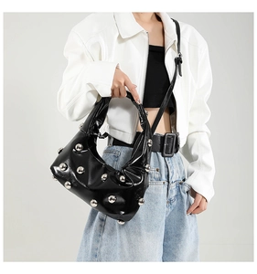Detail of black glossy patent leather shoulder bag with silver spherical metal studs