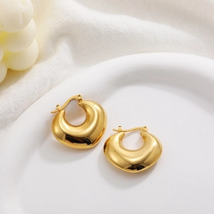 Detail of chunky 18K gold plated heart teardrop earrings on a white ceramic plate