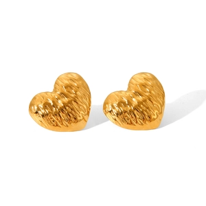 Macro view of golden heart-shaped earrings featuring a hammered texture finish