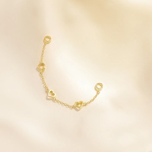 Detailed macro view of golden hollow heart charms on a delicate metal chain jewelry piece
