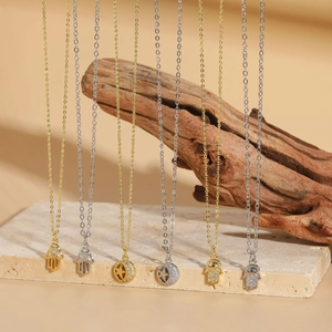 Dettaglio di ciondoli a mano di Hamsa e celesti con zirconi su collane in oro e argento