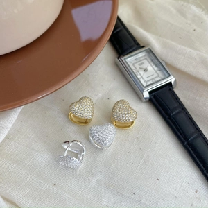 Macro view of heart-shaped gold and silver earrings with pavé cubic zirconia