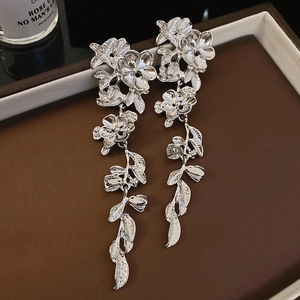 Elegant silver metallic flower leaf long tassel earrings on a brown jewelry tray