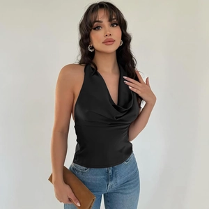 Front view of a sexy black satin backless halter top styled with classic blue jeans
