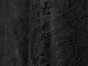 Black lace skirt with floral embroidery and mesh texture in a close-up detailed view